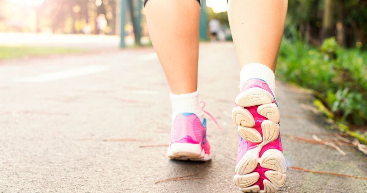 A person walking on a path in athletic shoes, illustrating post-meal walking for glucose control