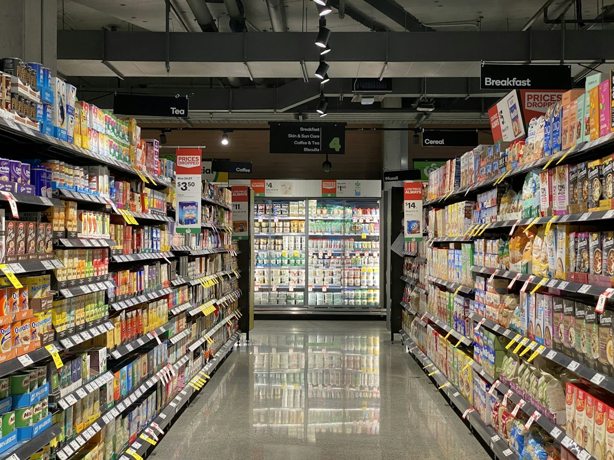 A shopper reading nutritional information on food packaging at a grocery store.