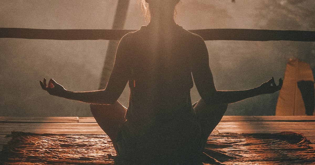 A person practicing meditation outdoors at sunrise, demonstrating mindful relaxation for stress relief