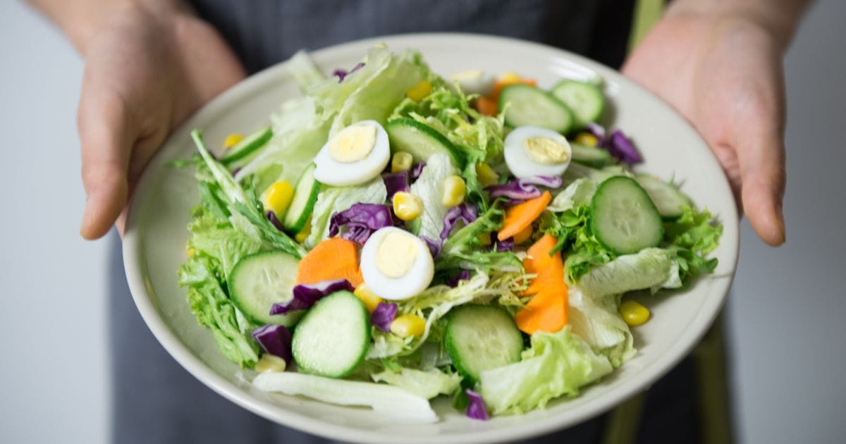 A colorful bowl of fresh vegetable salad with egg, representing fiber-rich foods that support blood sugar control