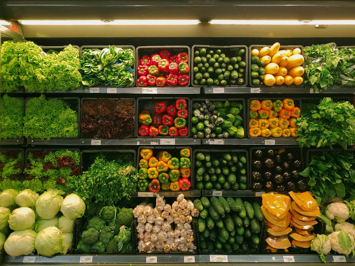 Fresh produce and packaged foods displayed in a well-lit supermarket aisle.